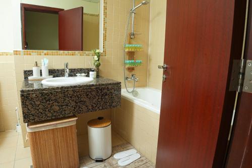 a bathroom with a sink and a bath tub at Pure Sand - Luxury Hostel JBR Dubai in Dubai
