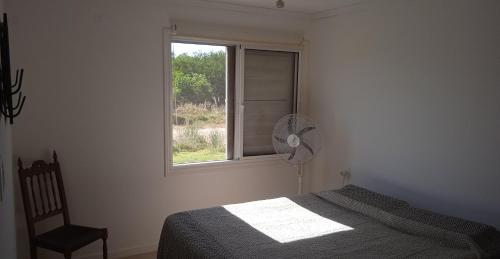 a bedroom with a bed and a fan and a window at Petrel in La Paloma