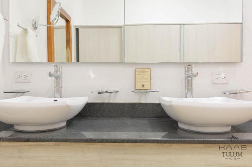 uma casa de banho com 2 lavatórios brancos e um espelho em Kaab Tulum em Tulum