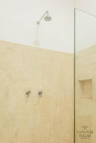 a shower with two faucets on a wall at Kaab Tulum in Tulum