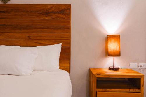 a bedroom with a bed and a lamp on a night stand at Kaab Tulum in Tulum
