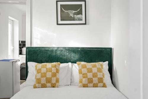 1 cama blanca con cabecero verde y 2 almohadas en 1 bedroom flat Aylesbury, Private Parking, Fowler rd, en Buckinghamshire