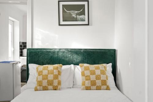 a white bed with a green headboard and two pillows at 1 bedroom flat Aylesbury, Private Parking, Fowler rd in Buckinghamshire