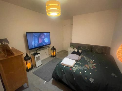a bedroom with a bed and a flat screen tv at Rhapsody Premium in Waltham Abbey