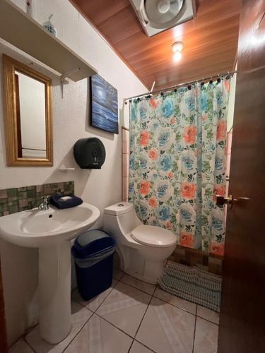 a bathroom with a toilet and a shower curtain at Hotel Sueños de María in Uvita