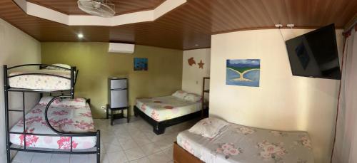 a room with two bunk beds and a flat screen tv at Hotel Sueños de María in Uvita