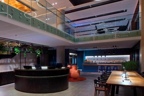 a restaurant with a bar with chairs and tables at Aloft Perth in Perth