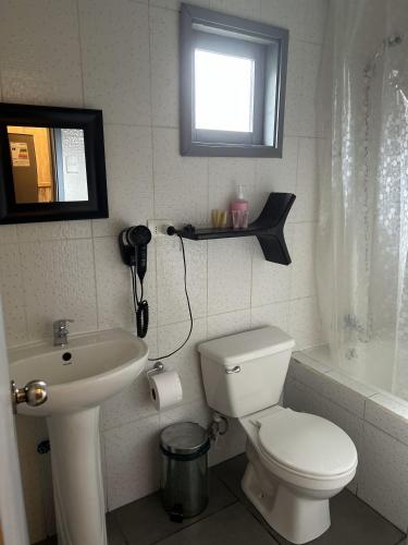 a bathroom with a white toilet and a sink at QUELEN AUSTRAL in Hornopiren