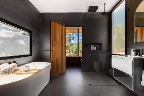 a bathroom with a tub and a sink and a window at CABN X Seppeltsfield Barossa in Seppeltsfield