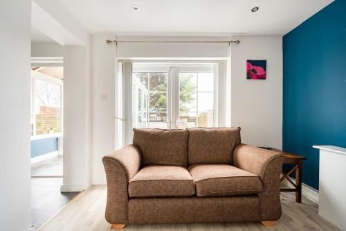 a couch in a living room with a blue wall at Lovely one bedroom flat. in Belfast