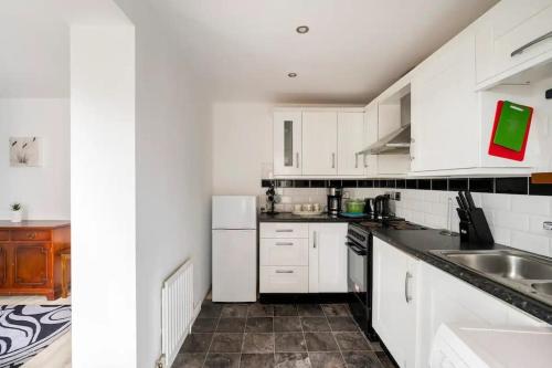 a kitchen with white cabinets and a sink at Lovely one bedroom flat. in Belfast