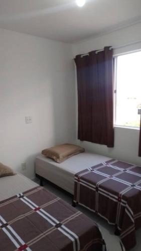 two beds in a room with a window at Campina Residence in Campina Grande