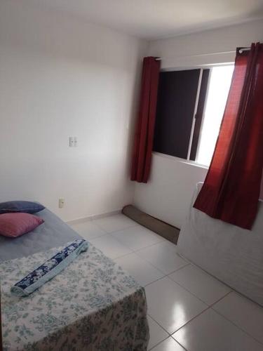 Schlafzimmer mit einem Bett und einem Fenster mit roten Vorhängen in der Unterkunft Campina Residence in Campina Grande