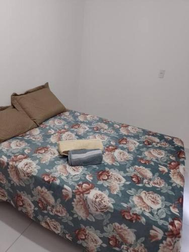 a bed with a flower patterned cover with a book at Campina Residence in Campina Grande