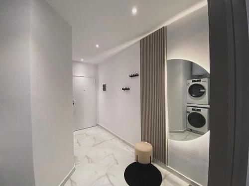 a white room with a washing machine and a stool at Suncity Tirana Luxury Apartments in Selitë e Vogël