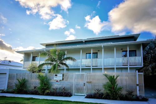 a white house with a fence and palm trees at MiHaven Shared Living - Gatton St in Cairns