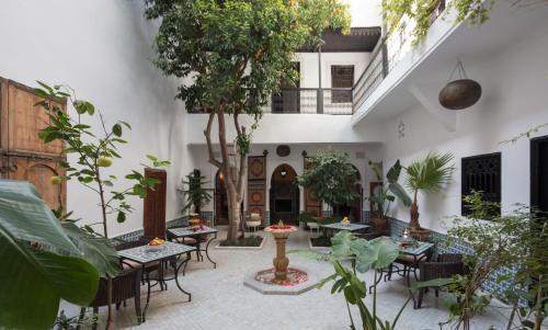 a courtyard with tables and chairs and plants at Origin Hotels Riad Lhena in Marrakesh