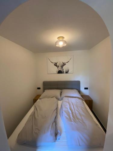 a bed in a bedroom with a cow picture on the wall at Das Hirscherl - Mountain Design Studio in Bad Kleinkirchheim