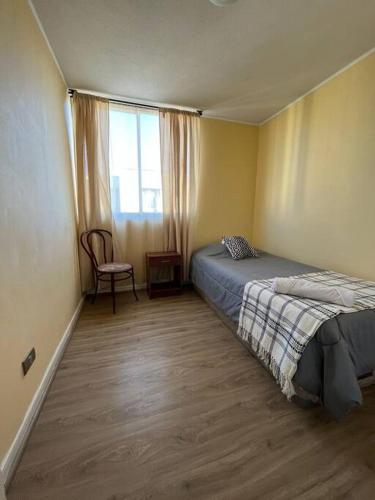 een slaapkamer met een bed, een stoel en een raam bij Departamento equipado 322 Ovalle in Ovalle