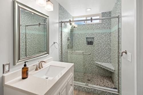 a white bathroom with a sink and a shower at Stunning Beach Home - large patio, parking, ac & dog friendly! in San Diego