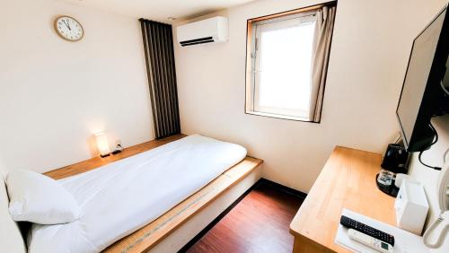 a small bedroom with a bed and a window at CHEZ LILY【旧:北海莊】 in Naha