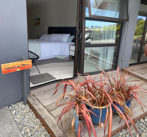 a bedroom with a bed and a potted plant on a porch at Sunrise on Main in Tairua