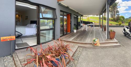 a house with a deck with a bed and some plants at Sunrise on Main in Tairua