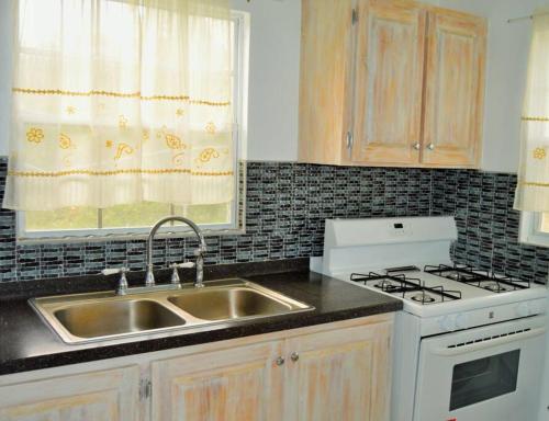 una cucina con lavandino, piano cottura e finestra di Pearl's Hilltop Cottage 