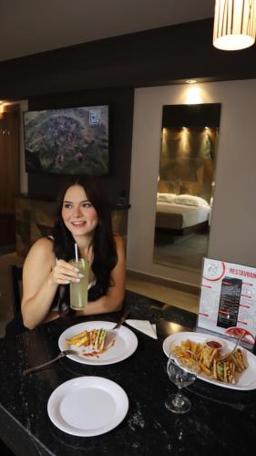 una mujer sentada en una mesa con platos de comida en Hotel Myst. en Monterrey