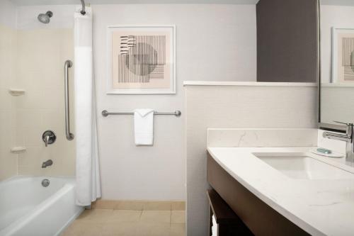 a bathroom with a white tub and a sink and a bath tub at Courtyard Jacksonville Flagler Center in Jacksonville