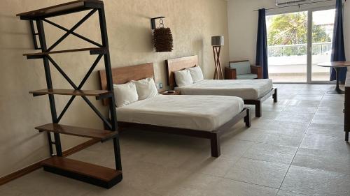 een kamer met 2 bedden en een boekenplank bij Ocean Drive Hotel in Isla Mujeres