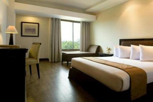 a hotel room with a large bed and a window at Opitalia Catalia Resort in Jakarta