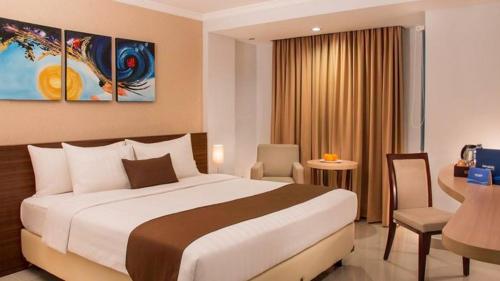 a hotel room with a large bed and a desk at Opitalia Catalia Resort in Jakarta