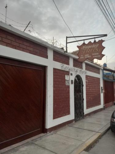 un edificio con dos puertas de garaje y un cartel en Hospedaje Flores, en Nazca