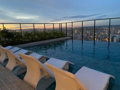 una piscina con sedie e vista sulla città di Studio Books Id Vida Urbana a Goiânia