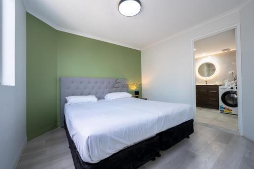 sypialnia z dużym białym łóżkiem i zieloną ścianą w obiekcie Abbey On Roma Hotel & Apartments w mieście Brisbane