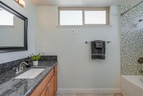 a bathroom with a sink and a tub and a window at Stunning South Mission Beach Home - AC, Private Patio, Grill and Garage! in San Diego