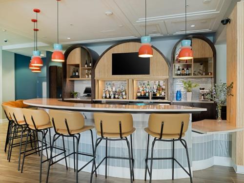 a bar in a restaurant with stools around it at voco Sarasota by IHG in Sarasota