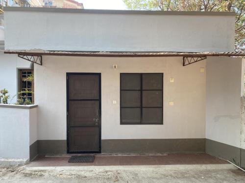 a small white house with a black door at Charming guesthouse in heart of Manipal in Manipala
