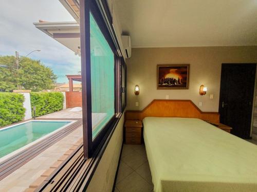 a bedroom with a bed and a swimming pool at CENTRO DE XANGRI-LÁ COM PISCINA in Xangri-lá