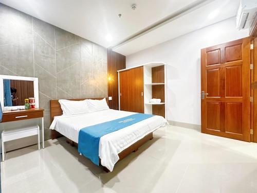 a bedroom with a bed and a table and a mirror at Milanesa Hotel and Apartment in Vung Tau