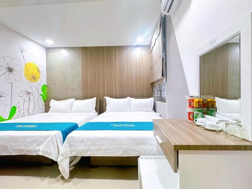 a hotel room with two beds and a desk at Milanesa Hotel and Apartment in Vung Tau