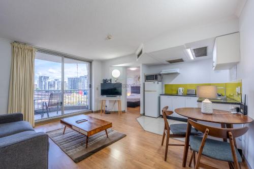 a living room with a table and a kitchen with a view at Abbey On Roma Hotel & Apartments in Brisbane
