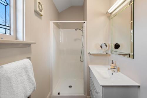 a white bathroom with a shower and a sink at Homelea Bed and Breakfast in Christchurch
