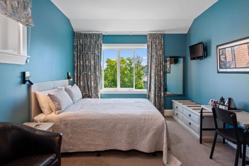une chambre bleue avec un lit et une fenêtre dans l'établissement Homelea Bed and Breakfast, à Christchurch