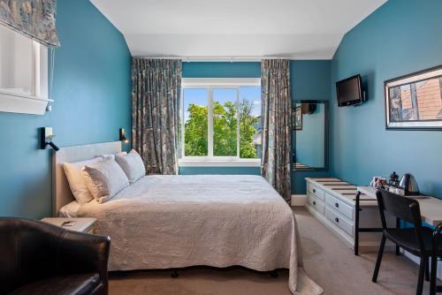 a blue bedroom with a bed and a window at Homelea Bed and Breakfast in Christchurch
