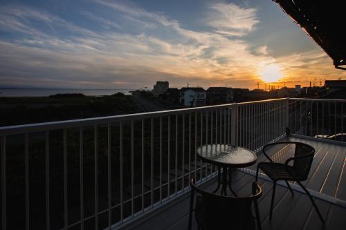 a balcony with a table and chairs and the sunset at のと千里浜リゾート in Hakui