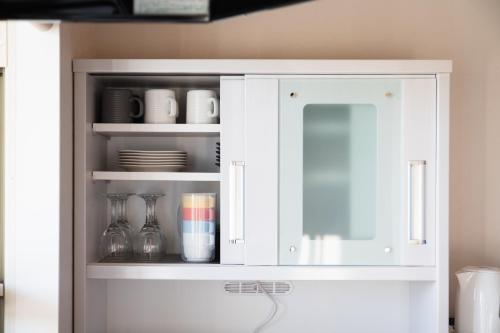 a white cabinet with plates and glasses in it at のと千里浜リゾート in Hakui