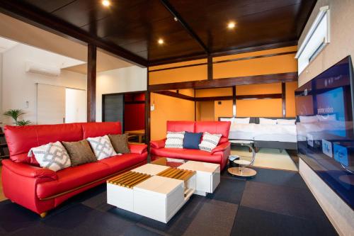 a living room with two red couches and a bed at のと千里浜リゾート in Hakui
