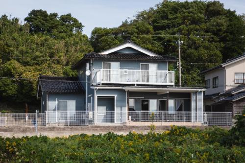 a blue house with a balcony and trees at のと千里浜リゾート in Hakui